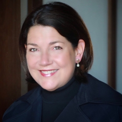 A woman with short, dark hair smiles at the camera